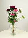 Vertical shot of a beautiful bouquet of asters in a glass vase, placed on a white table