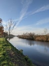 Vertical shot of a beautiful cloudscape over a calm reflective flowing river in Emden, Germany