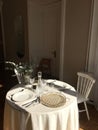 Vertical shot of a beautiful interior with a small round table with a tablecloth and cutlery