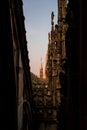 Vertical shot of a beautiful view of Duomo di Milano from a dark narrow alley in Milan, Italy