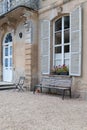 Vertical shot of a Bench and flowers in front of a high window of Martragny castle Royalty Free Stock Photo