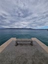 Vertical shot of a bench with the view of a seascape under the big white clouds Royalty Free Stock Photo