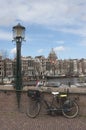 Vertical shot of a bicycle parked on a bridge in the beautiful city of Amsterdam during dayli Royalty Free Stock Photo