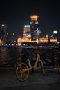 Vertical shot of a bicycle on a street with city view of Shanghai in China at night