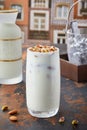 Vertical shot of a big glass of Horchata with nuts on the table with blur background