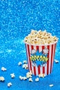 Vertical shot of a big paper cup filled with popcorn on a shiny blue surface Royalty Free Stock Photo