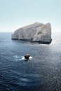 Vertical shot of a big rock in the middle of the sea with a blue sky in the background Royalty Free Stock Photo