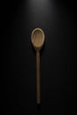 Vertical shot of a big wooden spoon isolated on black background Royalty Free Stock Photo