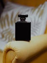 Vertical shot of a black aesthetic perfume bottle on yellow furniture