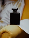 Vertical shot of a black aesthetic perfume bottle on yellow furniture