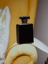 Vertical shot of a black aesthetic perfume bottle on yellow furniture