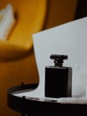 Vertical shot of a black aesthetic perfume bottle on yellow furniture