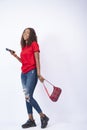 Vertical shot of a black female holding a phone and swinging a handbag