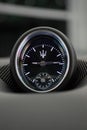 Vertical shot of a black Maserati Levante dashboard clock in a blurred background