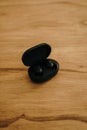 Vertical shot of black wireless earbuds on a wooden table Royalty Free Stock Photo