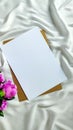 Vertical shot of blank paper with purple roses on the piece of white cloth Royalty Free Stock Photo
