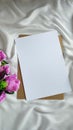 Vertical shot of blank paper for romantic letter with purple flowers on the piece of white cloth Royalty Free Stock Photo