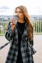 Vertical shot of a blonde woman enjoying her cup of coffee on a windy day. Royalty Free Stock Photo