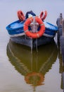 Vertical shot of a blue boat with some lifebuoys in vivid orange color