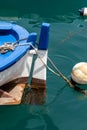 Vertical shot of a blue classic fishing boat hanging in the dark turquoise water at the harbor Royalty Free Stock Photo