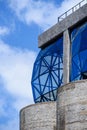 Vertical shot of blue glass paned window bulging out from concrete frames - artistic architecture