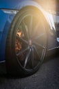 Vertical shot of a blue Hyundai Genesis Coupe luxurious car wheel with a sunbeam on the street