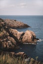 Vertical shot of the blue sea and a rock on a cloudy day Royalty Free Stock Photo