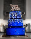 Vertical shot of a blue three-tier sweet sixteen birthday cake decorated with candies Royalty Free Stock Photo