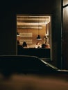 Vertical shot of blurry people seen through a cafe window in the evening. Royalty Free Stock Photo