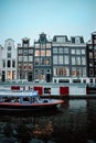 Vertical shot of the boat in river with Famous looking buildings in Amsterdam