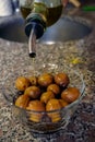 Vertical shot of a bottle of olive oil pouring onto green olives in a bowl Royalty Free Stock Photo