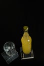 Vertical shot of a bottle of orange juice, lemonade, alcoholic beverage and an empty glass standing on black wooden table Royalty Free Stock Photo