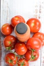 Vertical shot of a bottle of tomato juice and raw whole tomatoes on a white wooden background