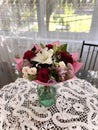 Vertical shot of a bouquet of flowers in a vase on the table with windows in the blurry background Royalty Free Stock Photo
