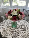 Vertical shot of a bouquet of flowers in a vase on the table with windows in the blurry background Royalty Free Stock Photo