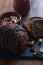 Vertical shot of a bowl of cashews next to the cup and rye bread