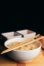 Vertical shot of a bowl of cooked rice with chopsticks on it on the table with sauces Royalty Free Stock Photo