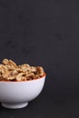 Vertical shot of a bowl full of walnut kernels with a black background Royalty Free Stock Photo