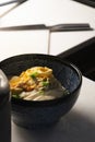 Vertical shot of a bowl of noodle and vegetables on a white table