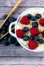 Vertical shot of a bowl of oats with yogurt, raspberries, and blueberries on the table with a tool Royalty Free Stock Photo