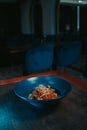 Vertical shot of a bowl of spaghetti with sauce and grated cheese on the table in a restaurant Royalty Free Stock Photo