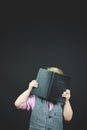 Vertical shot of a boy in a cool costume reading the holy bible on a black background Royalty Free Stock Photo