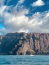 Vertical shot of the breathtaking view of the cliffs over the ocean under the beautiful clouds