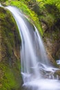 Vertical shot a breathtaking waterfall over the beautiful moss-covered rocks in a lake Royalty Free Stock Photo