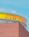 Vertical shot of a brick building with a circle glass tunnel under the blue sky