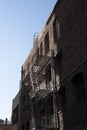 Vertical shot of a brick building with a fire escape staircase and a blue sky in the background Royalty Free Stock Photo