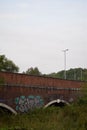 Vertical shot of a bridge with graffiti and lightposts