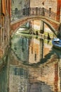 Vertical shot of a bridge over the canal in Venice, Italy with reflections in the water Royalty Free Stock Photo