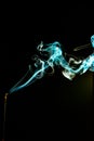 Vertical shot of bright blue incense smoke on a black background Royalty Free Stock Photo