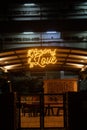 Vertical shot of bright yellow neon Garden of Love sign hanging from the cafe roof